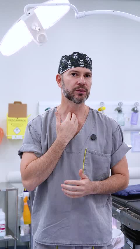 Médico paramentado falando para a câmera em centro cirúrgico